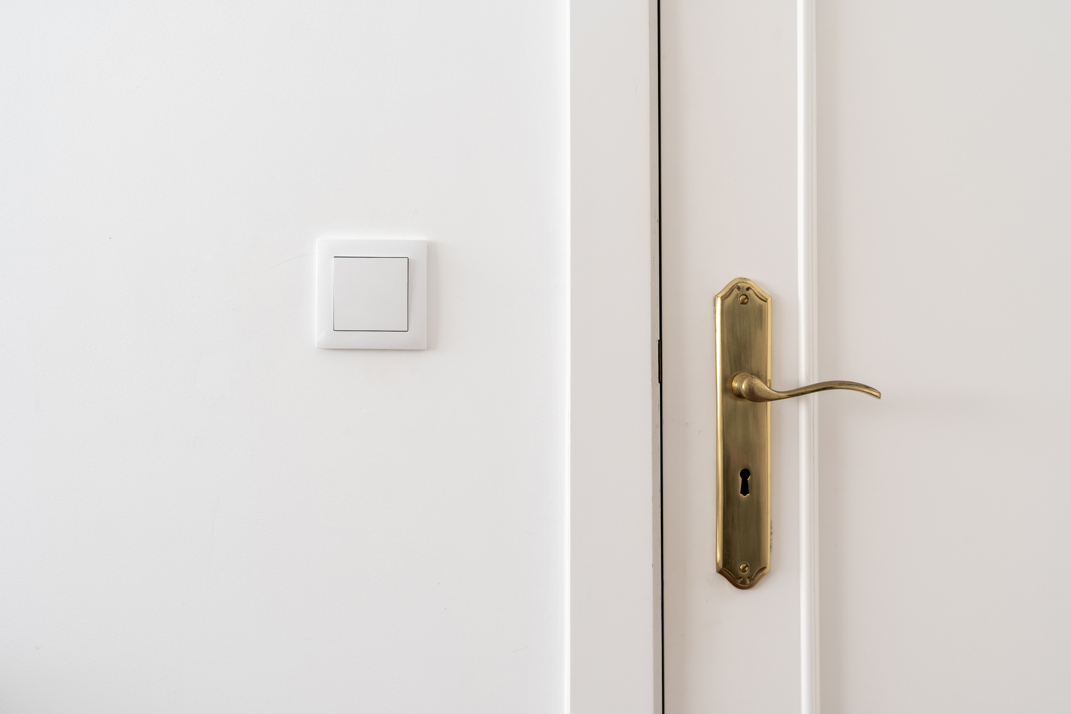 Imagem de uma porta de madeira branca com fechadura dourada.