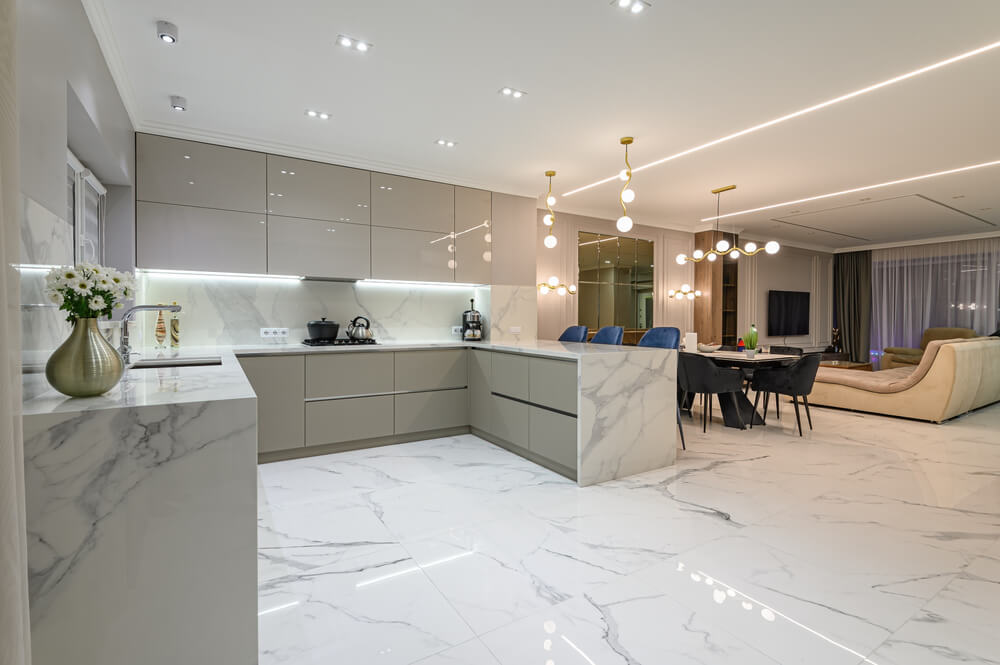 Foto que ilustra matéria sobre tipos de piso mostra um piso de mármore em ambientes integrados: cozinha, sala de jantar e sala de estar.