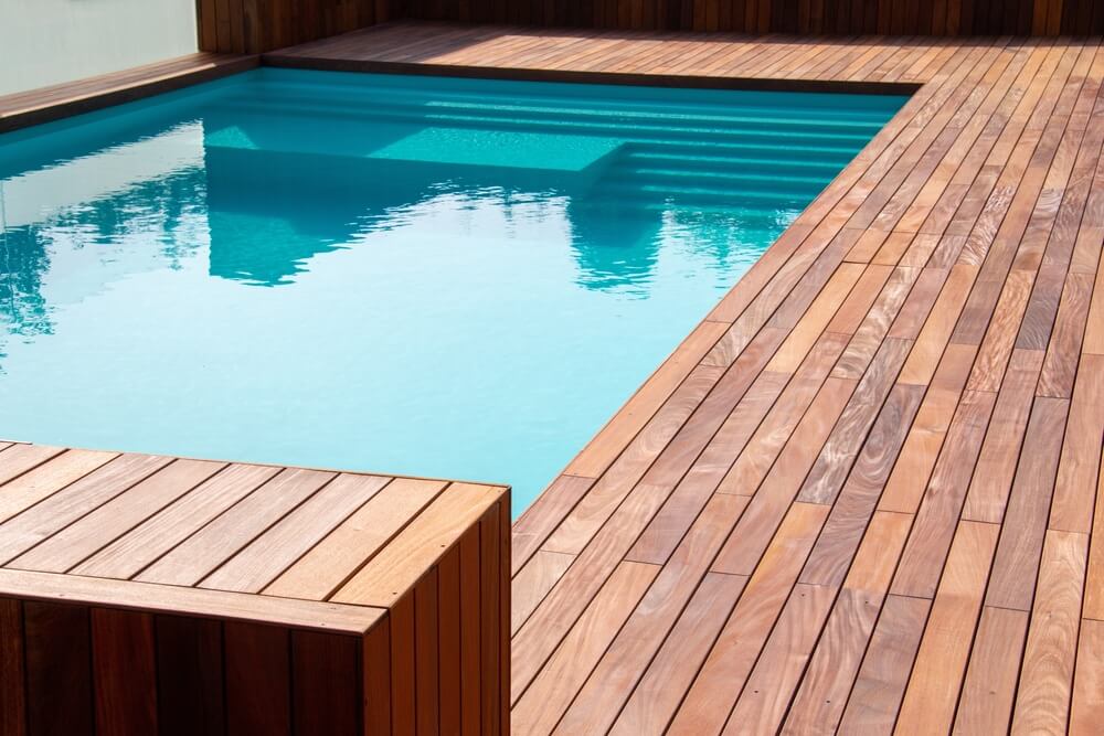 Foto que ilustra matéria sobre tipos de piso mostra uma piscina cercada por um deck de madeira.