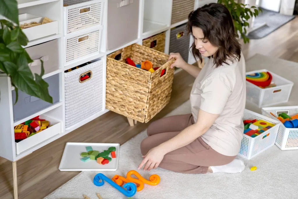 Imagem de uma mulher organizando os brinquedos de uma criança em caixas para ilustrar matéria sobre o trabalho de um consultor de arrumação