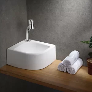 Foto que ilustra artigo sobre modelos de pia de banheiro mostra uma pia de canto em cima de uma bancada de madeira