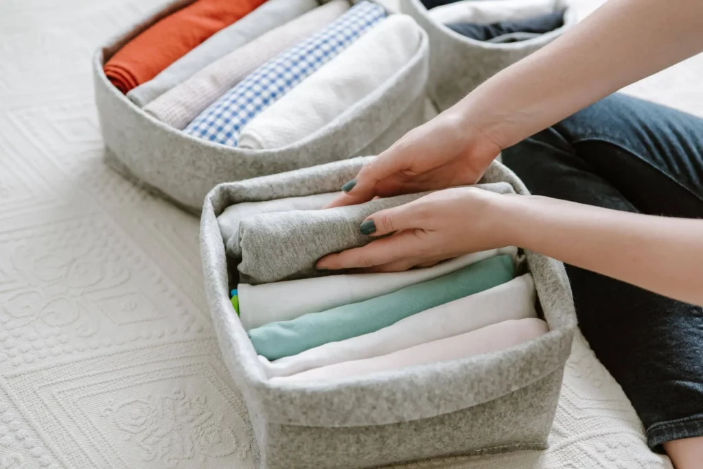 Imagem de uma pessoa guardando roupas em caixas e cestas para ilustrar matéria sobre o que é personal organizer