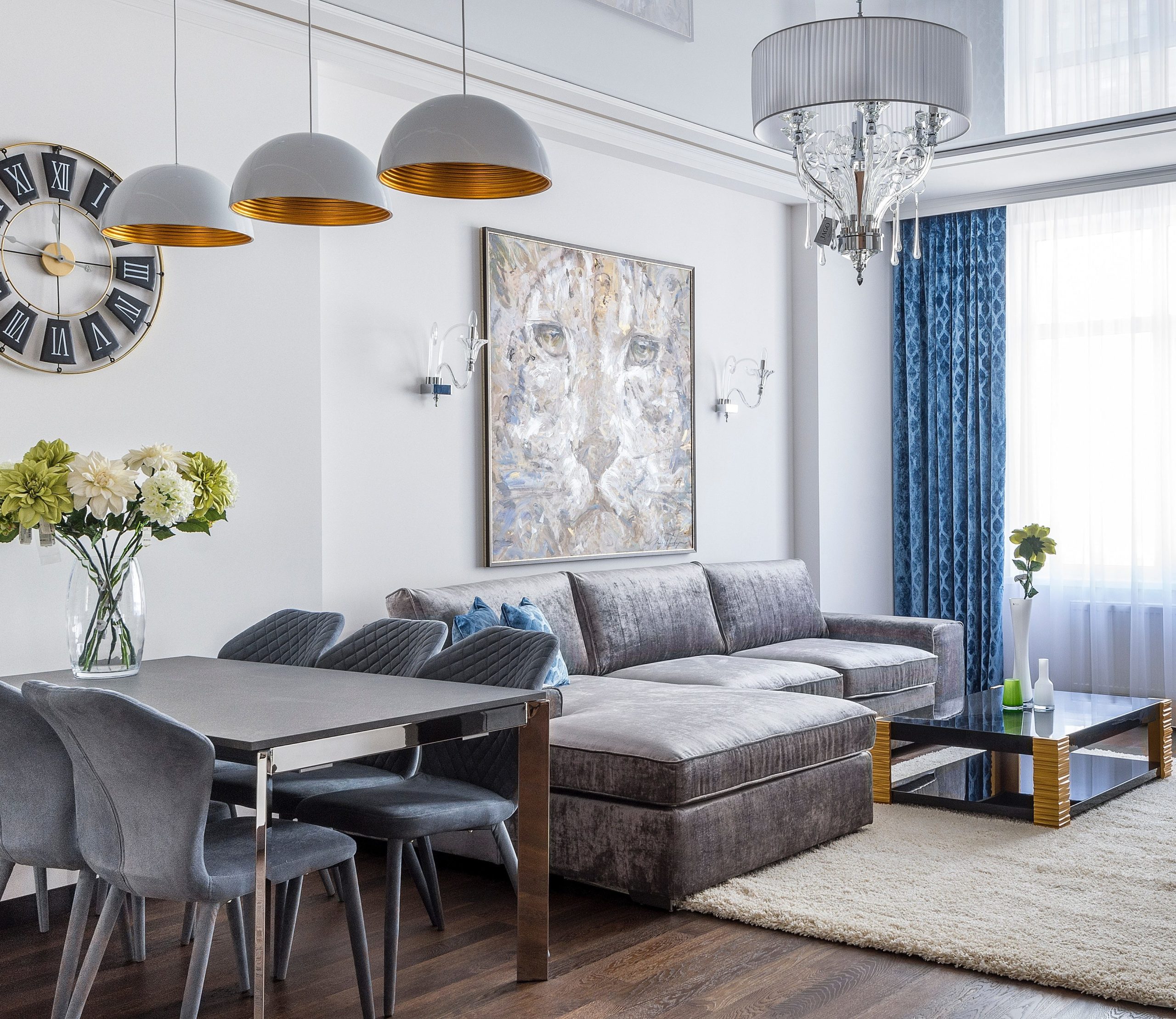Sala de estar integrada com sala de janta em tons de cinza e cortina azul estampada. 