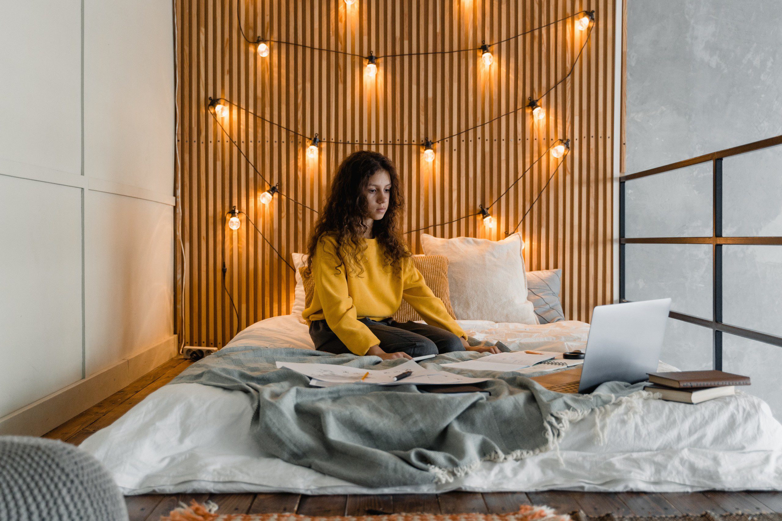 Imagem de um painel de madeira ripado com luzinhas instalado como cabeceira de cama.