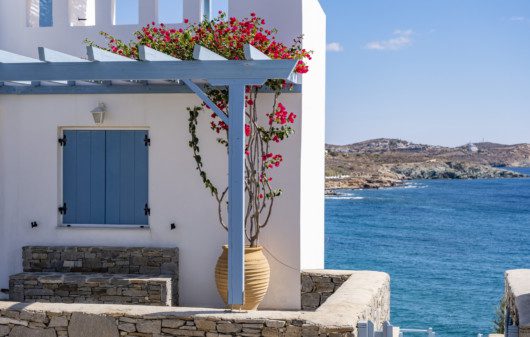 decoração de casa grega, na cor branca, com pergolado azul e flores rosas