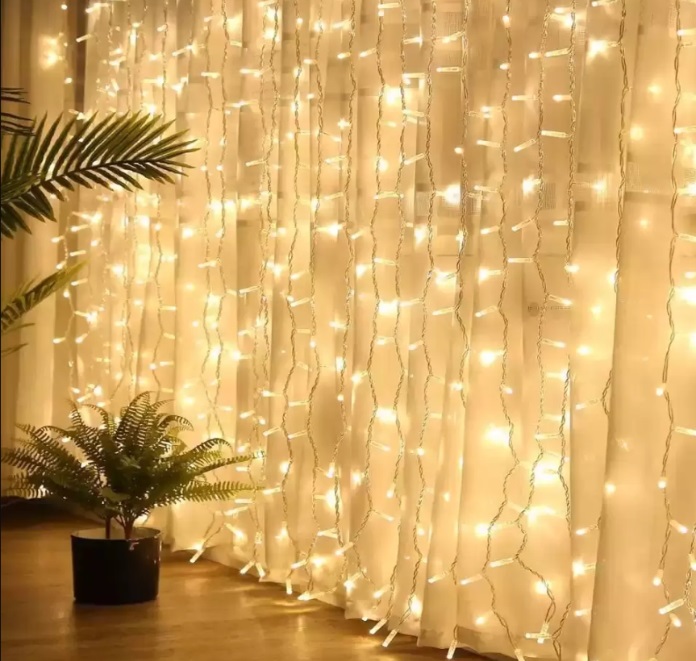 Foto que ilustra matéria sobre decoração de Ano Novo mostraluzes de led à frente de uma cortina branca.