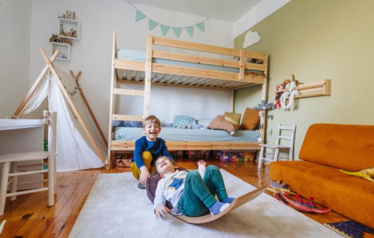 Imagem de dois meninos brincando em seu quarto.