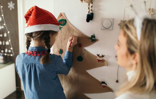 Imagem de mãe e filha decorando a casa para o Natal.