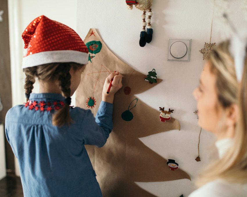 Imagem de mãe e filha decorando a casa para o Natal.
