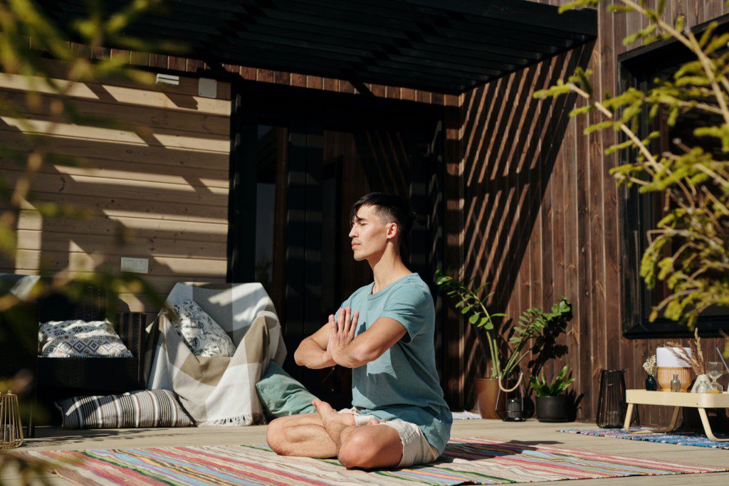 Homem faz meditação em seu cantinho zen decorado com plantas.