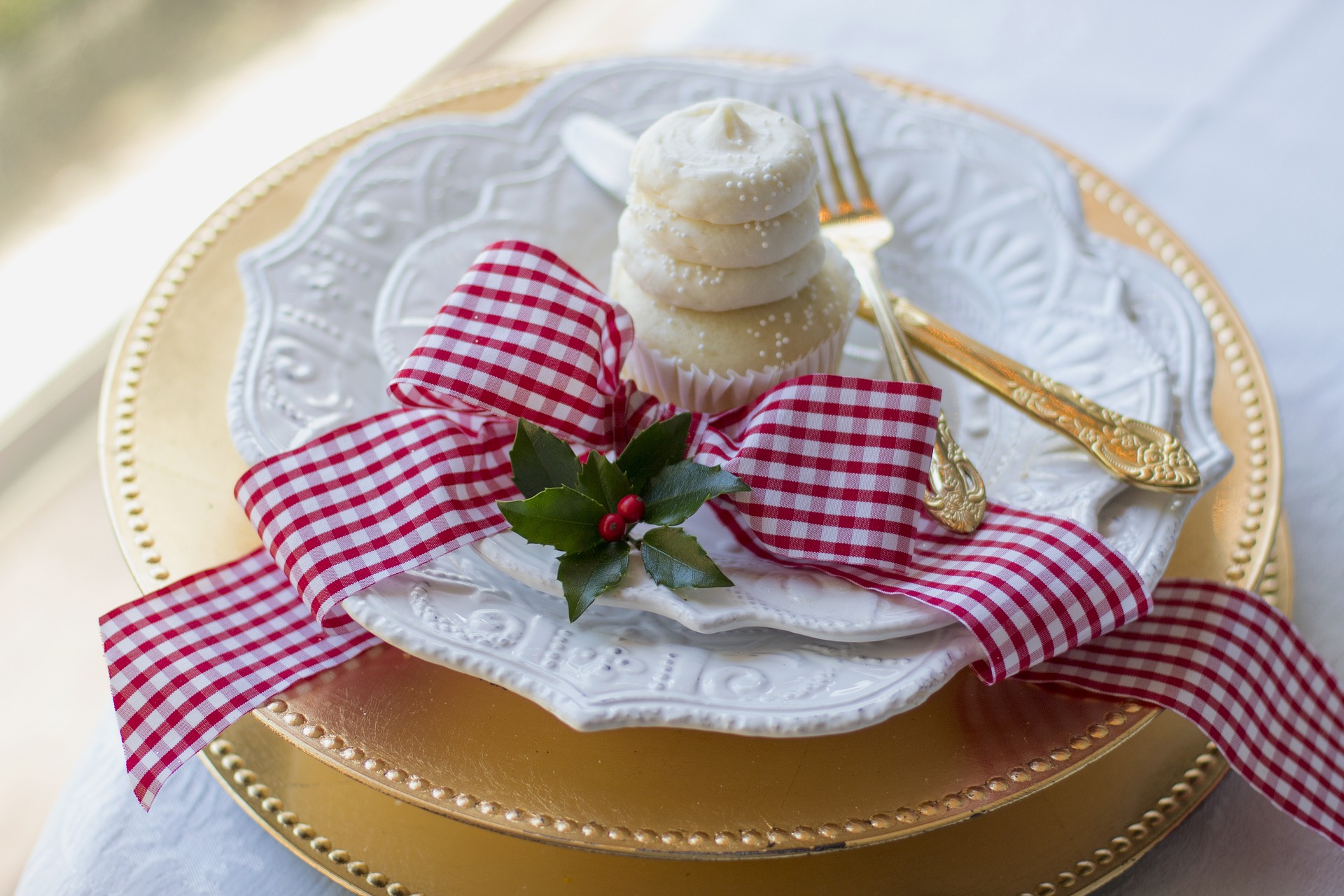 Imagem de um laço vermelho xadrez decorando os pratos de uma mesa de Natal.