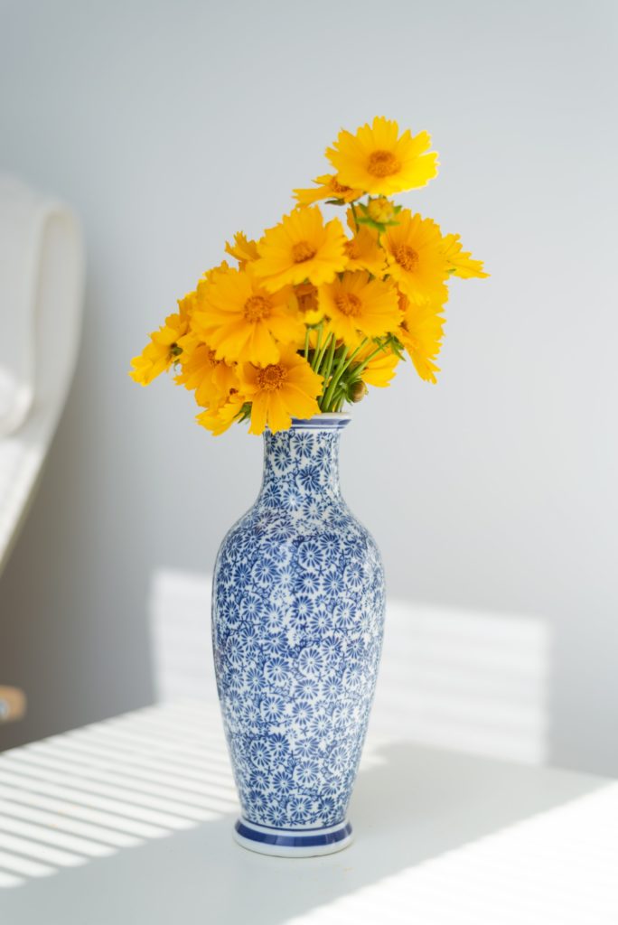 Já em uma decoração grega com contrastes, flores amarelas em vaso azul e branco