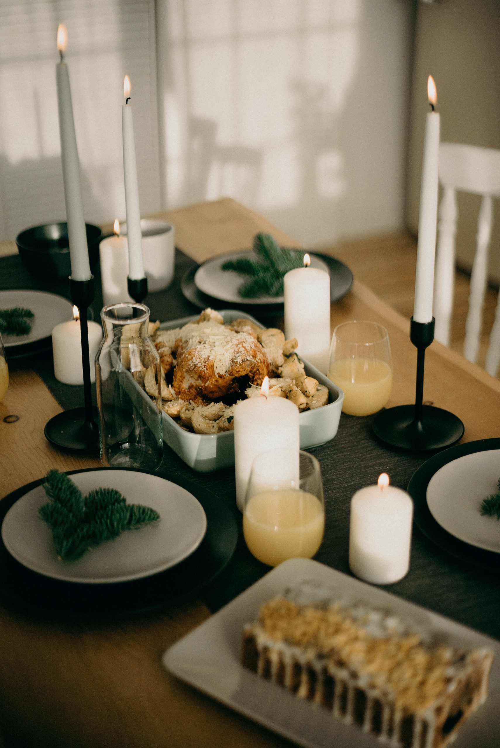 Mesa de Natal minimalista com pratos branco, porta-velas e sousplat preto.