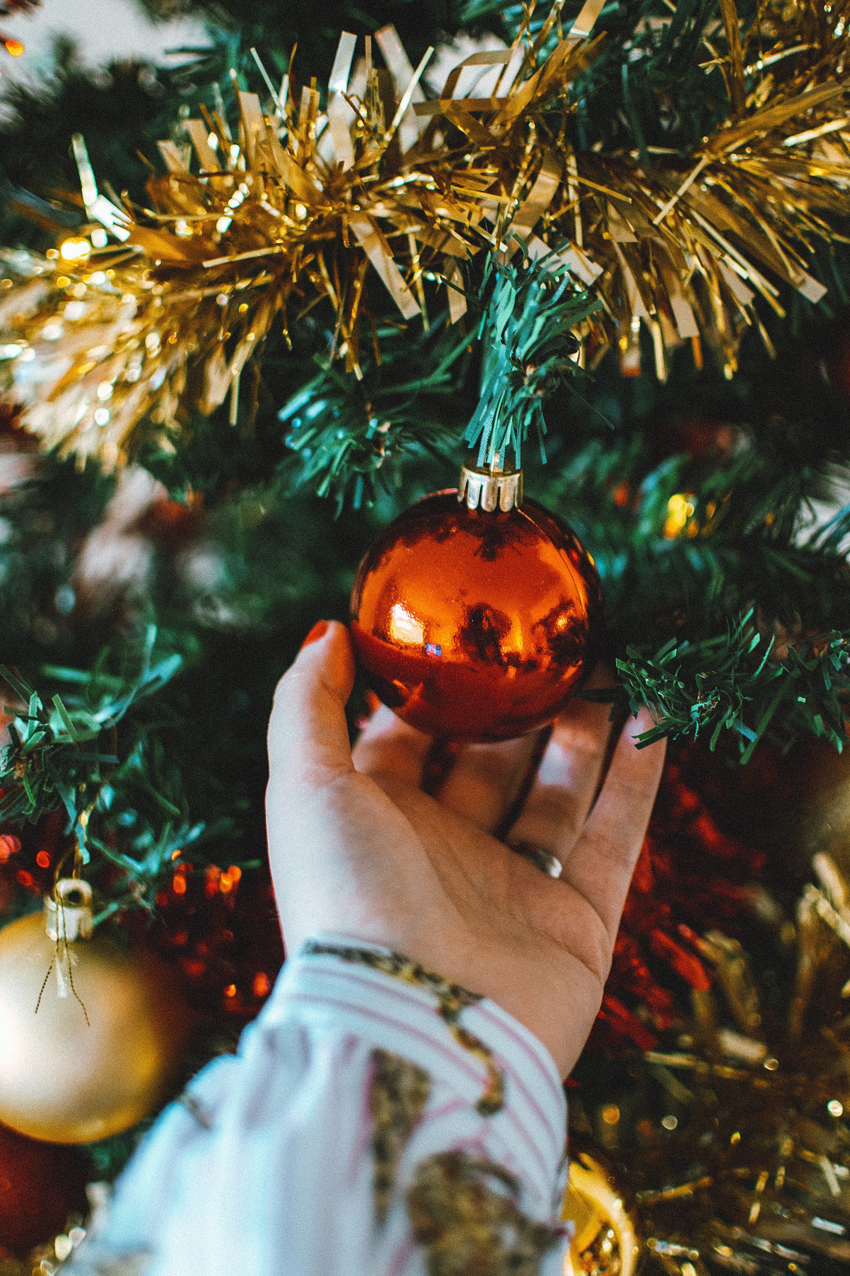 Imagem de uma mão segurando uma bola de Natal.