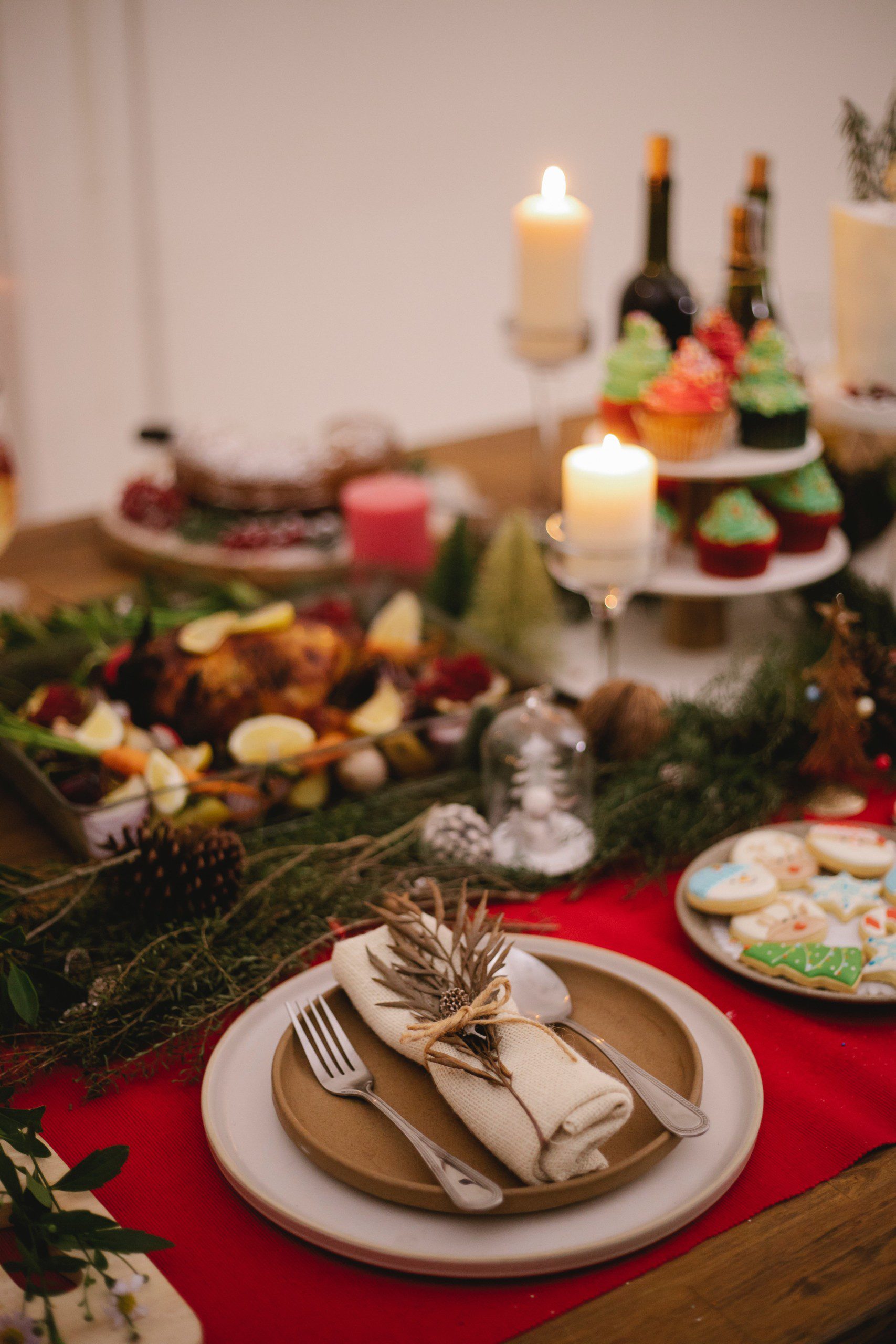 Mesa de Natal com frutas, cupcakes e decoração com galhos secos e pinha. 