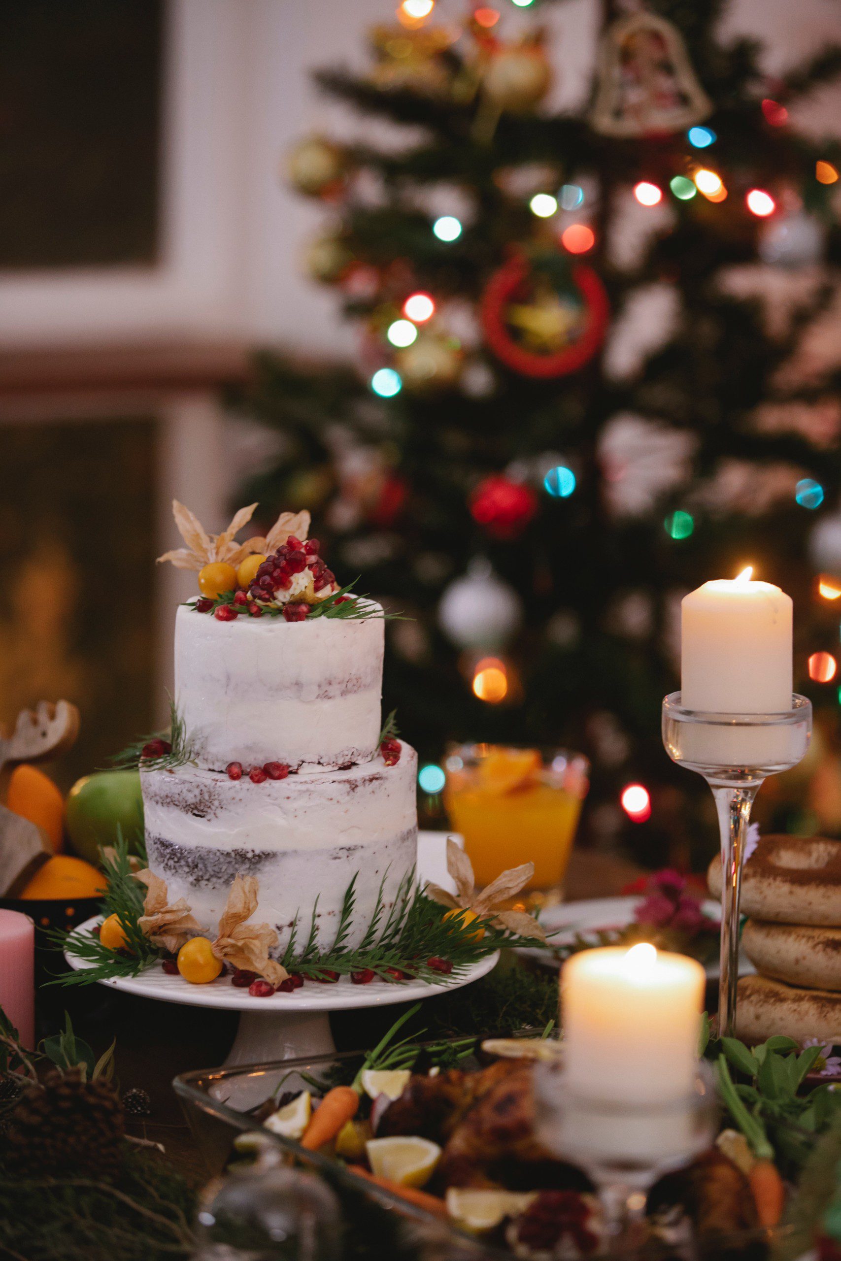 Bolo natalino, porta-velas em cristal e uma árvore de Natal ao fundo.