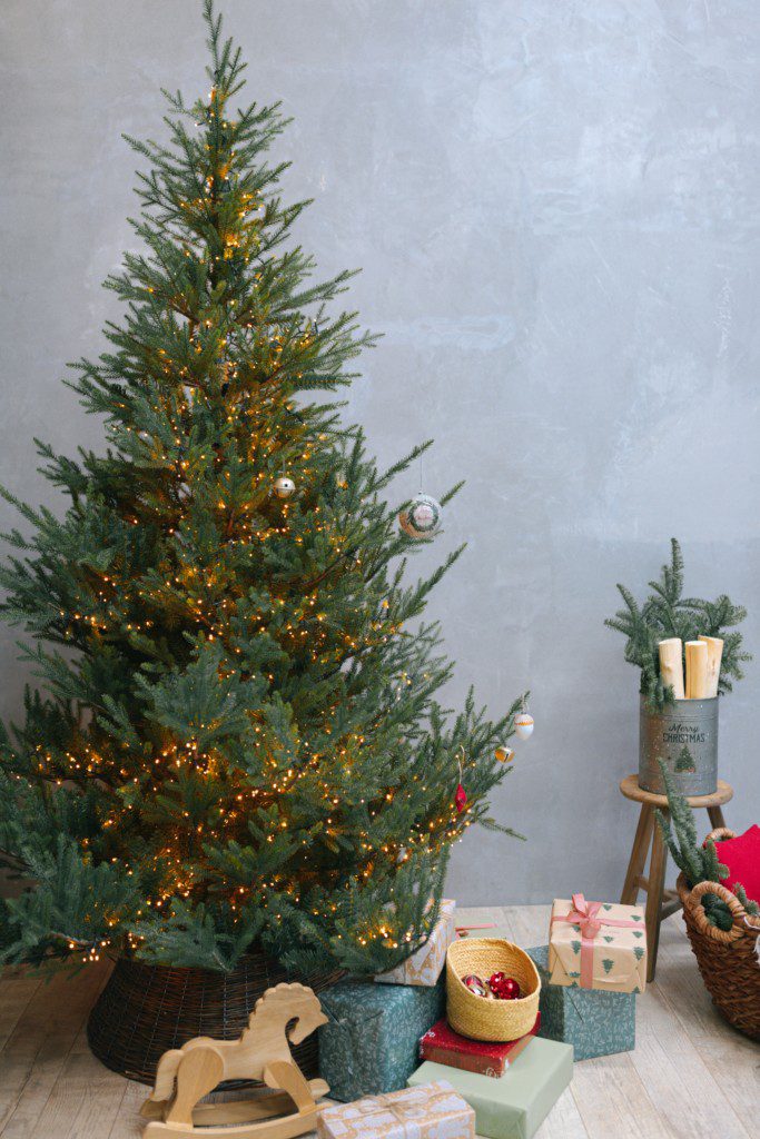 Imagem de um pinheiro com luzinhas e enfeites de Natal.