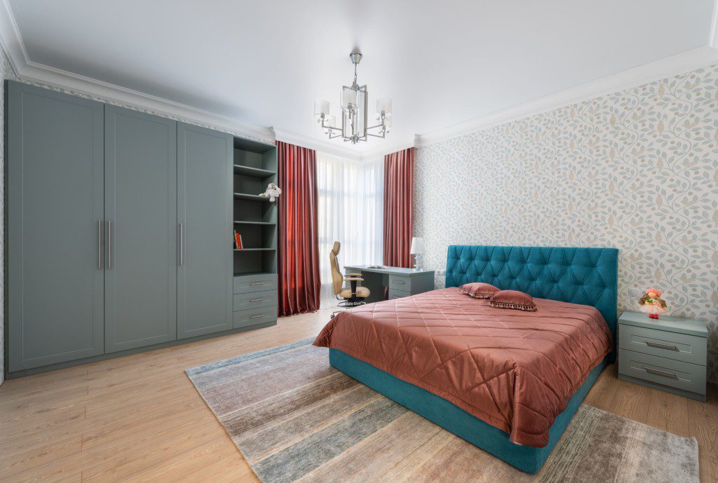 Quarto de luxo com tapete colorido ao redor do pé da cama. imagem disponível em Pexels.