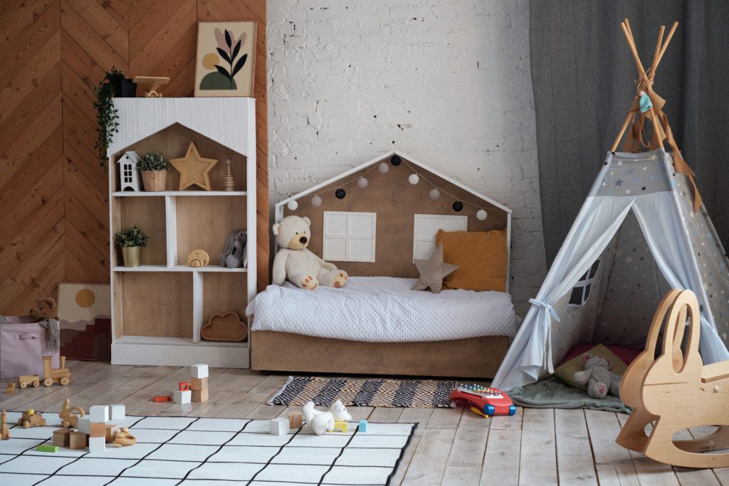 Foto de um quarto infantil com diferentes elementos de fácil acesso à criança: cama, estante, cabana, brinquedos. 