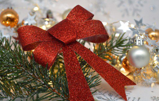 Laço de Natal vermelho junto com alguns galhos, bolas e luzes,