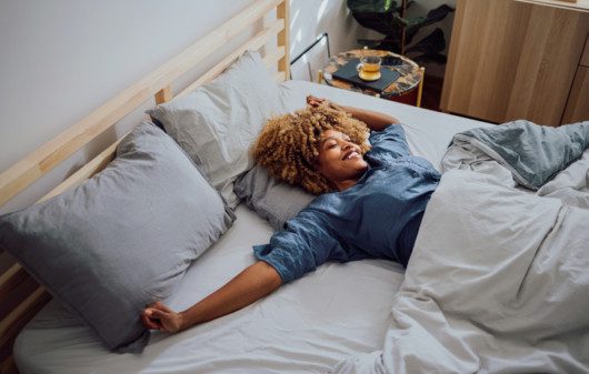 Imagem de uma mulher se espreguiçando na cama.