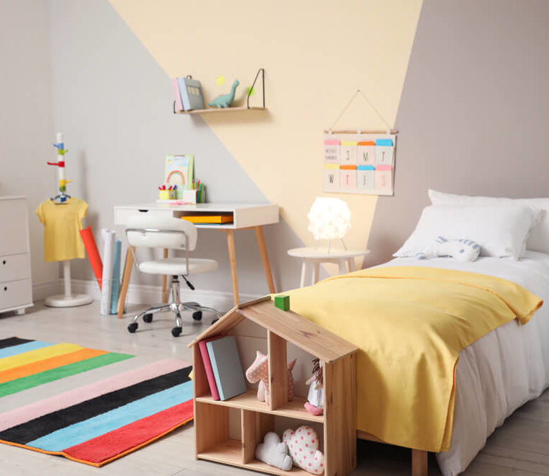 Pintura setorizada em um quarto de criança ajuda a destacar a parede onde estão encostadas a cama e uma escrivaninha.