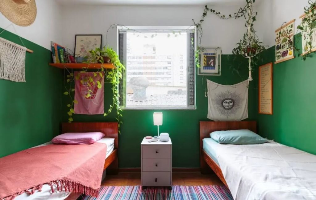 Foto que ilustra matéria sobre pintura setorizada mostra um quarto que tem todas as suas paredes pintadas de verde escuro da metade para baixo. 