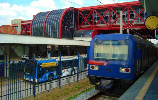 Foto que ilustra matéria do Terminal Grajaú mostra, lado a lado, plataformas de ônibus (à esquerda da imagem) e de trem da CPTM. Acima delas, há uma estrutura vermelha de passarela.