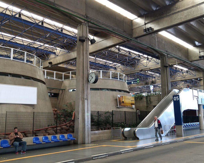 Foto mostra uma estrutura coberta do Terminal Jabaquara, com um nível mais baixo na altura da rua e uma escada rolante que leva ao nível de cima.