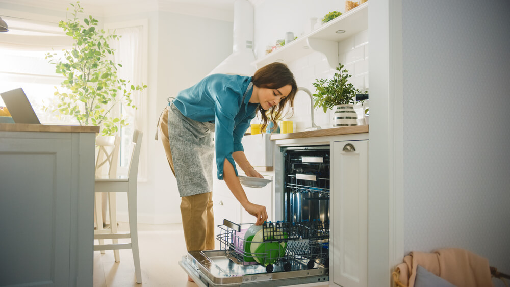 Foto que ilustra matéria sobre consumo consciente de água mostra uma mulher colocando pratos em uma lavadoura de louças