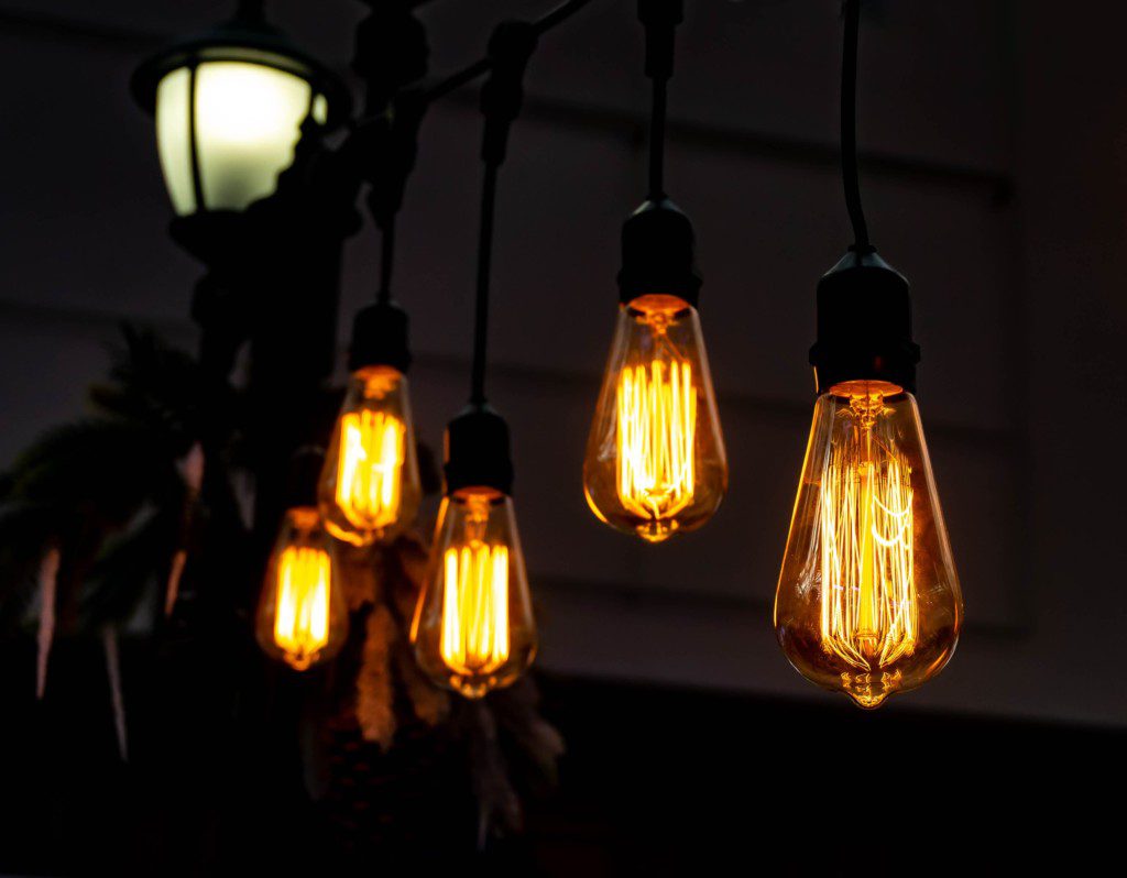 Luminárias com lâmpadas incandescentes e pendentes, estilo industrial. Imagem disponível em Getty Images.