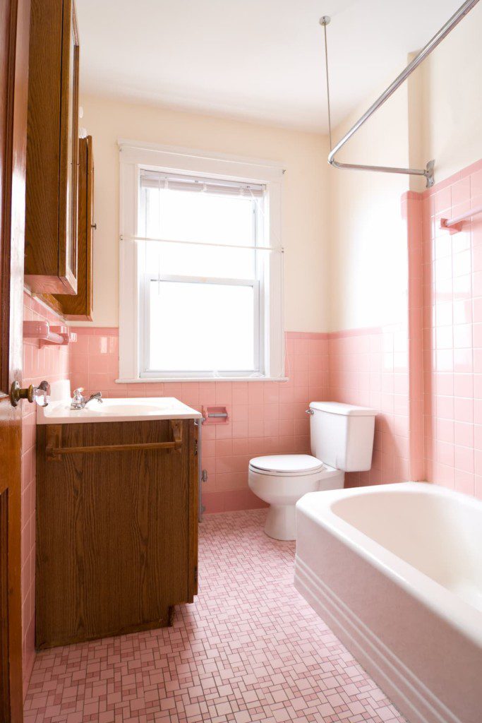 Banheiro retrô rosa e branco, em tons pastéis. Imagem disponível em Getty Images.