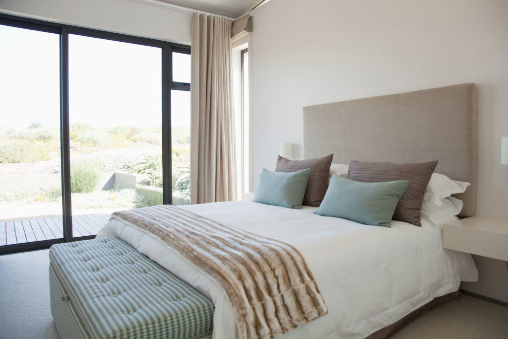 Quarto moderno com a cama posta participando da decoração do ambiente. Imagem disponível em Getty Images.
