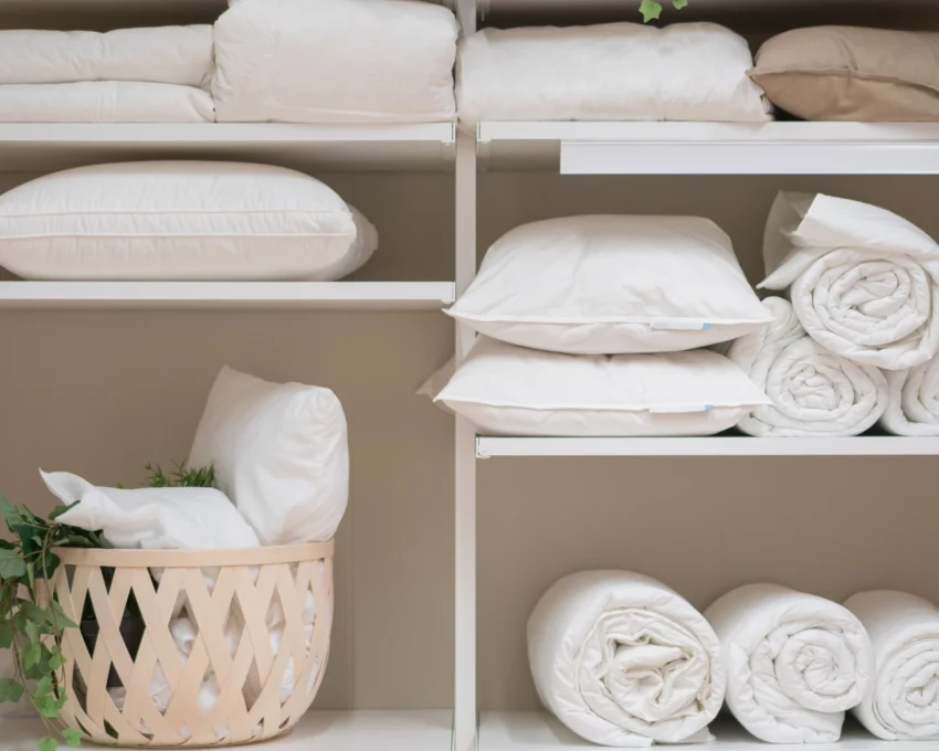Imagem de um armário aberto com várias roupas de uso doméstico, como toalhas, edredom e travesseiros, todos brancos, para ilustrar matéria sobre como clarear roupa branca