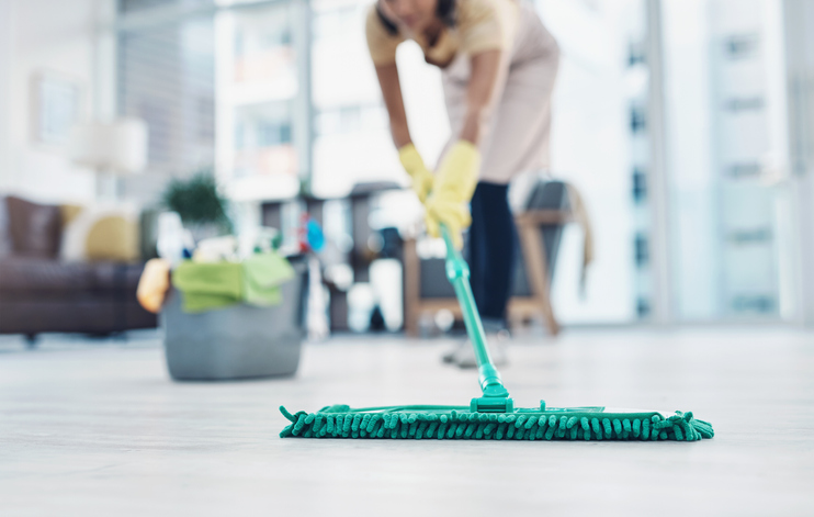Imagem de uma mulher limpando o chão com um Mop de algodão.
