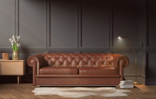 Foto que ilustra matéria sobre a técnica capitonê de estofamento mostra um sofá de couro marrom.