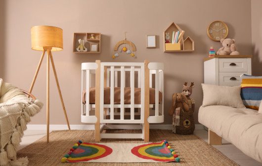 Quarto de bebê com berço, tapete colorido, prateleiras e nichos decorativos.