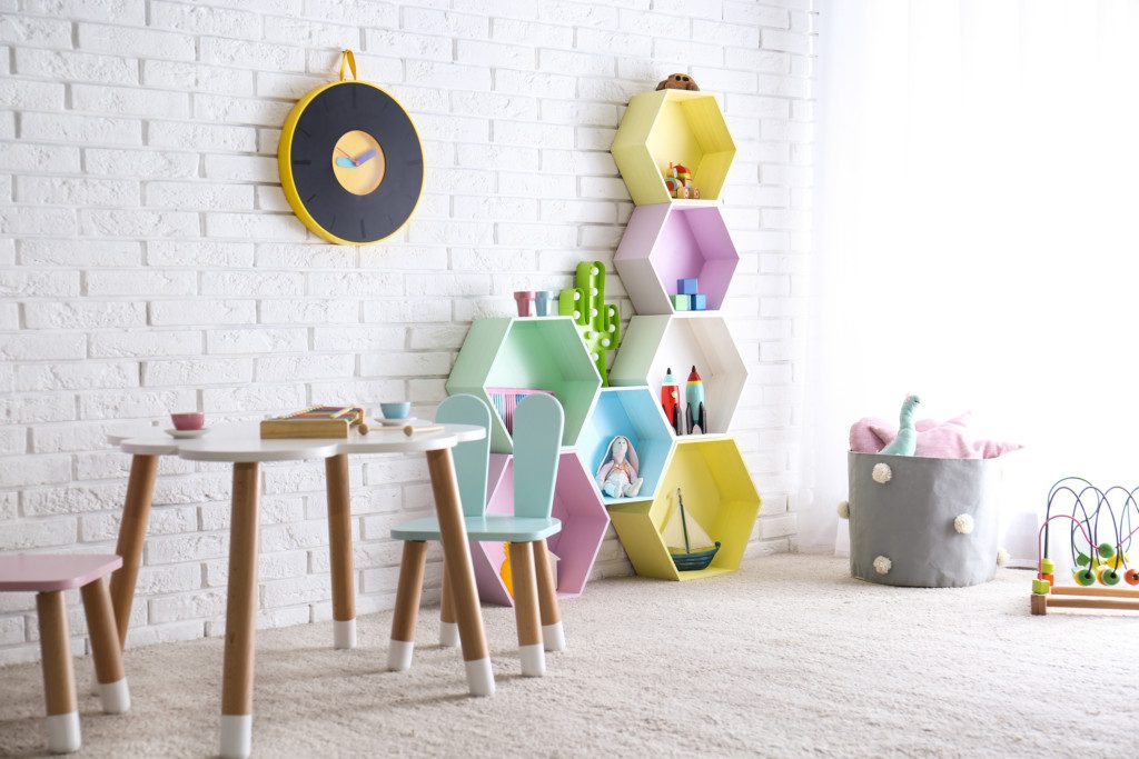 Imagem que ilustra matéria sobre quarto de brinquedos mostra um quarto de brinquedos com prateleiras de colmeia e mesinha 

