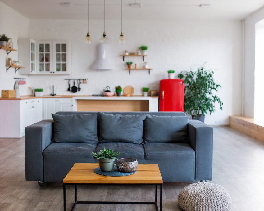 Imagem de uma sala moderna integrada com uma cozinha em tons de cinza, branco, madeira e vermelho.