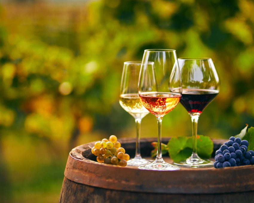 Imagem de três taças diferentes de vinho encima de um barril.