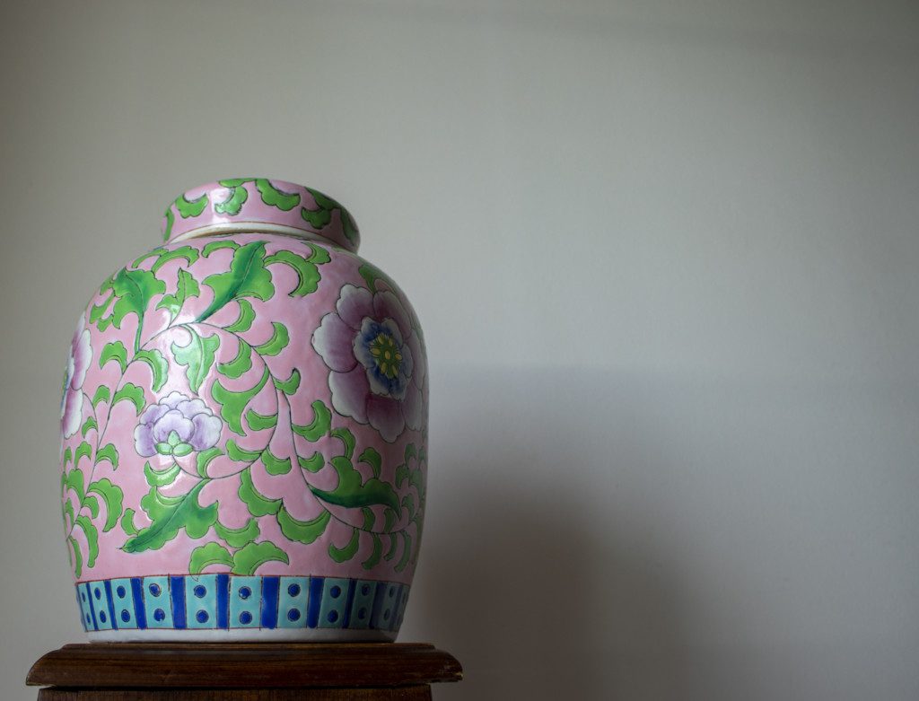 Vaso decorativo pintado à mão com flores rosa, verde e detalhes em azul.