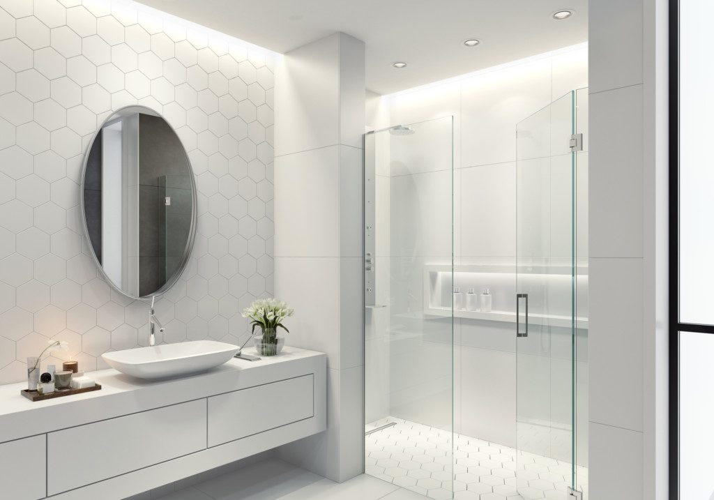 Foto de um banheiro branco com azulejos de pedra natural e azulejos hexagonais. Tem também uma pia longa e grande espaço de banho, além de um espelho oval e arredondado.