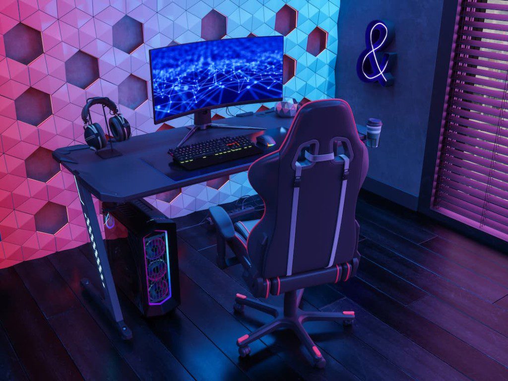 Escritório geek com computador, escrivaninha e cadeira gamer.