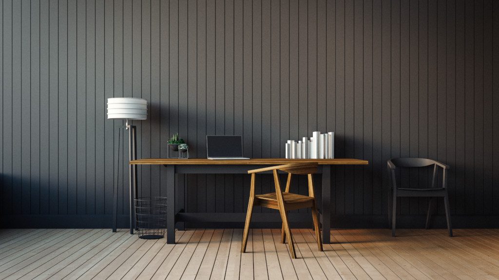 Foto de um escritório em tons de preto com apenas o essencial: escrivaninha, luminária de chão, notebook, duas cadeiras.