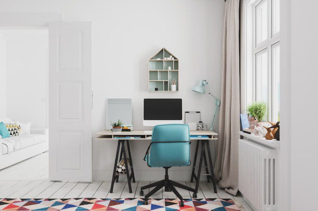 Home office minimalista com luminária de mesa e janela ao lado.
