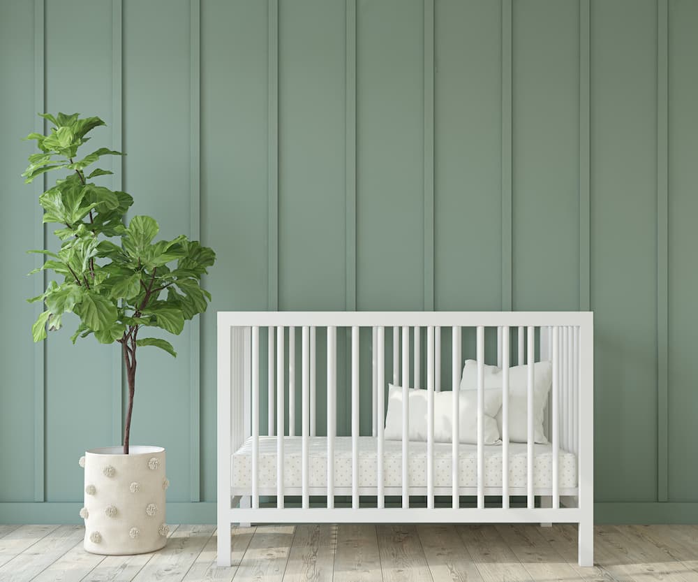 Quarto de bebê retrô com berço branco e parede verde.