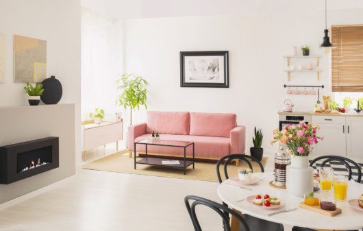 Imagem de uma kitnet com sofá rosa, espaços integrados e lareira.