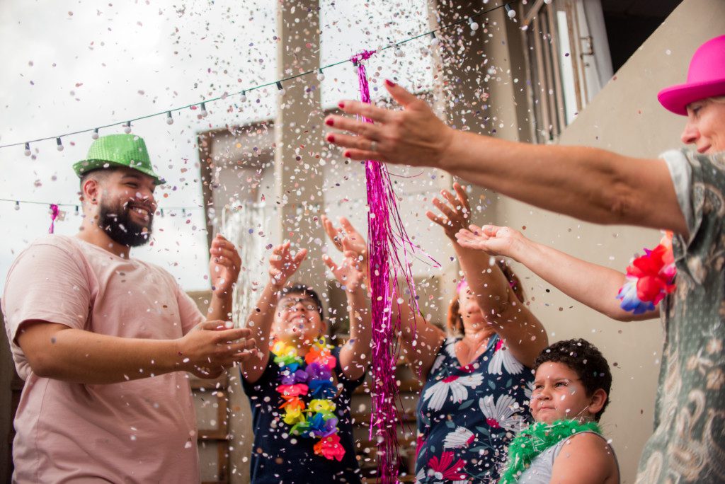 Família festejando o carnaval com confete, purpurina e fantasias.