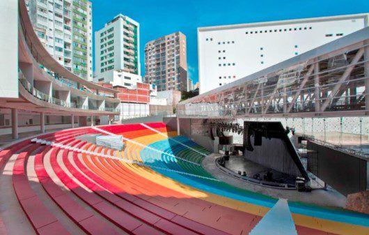 Foto que ilustra matéria sobre a Concha Acústica de Salvador mostra o espaço visto de cima das arquibancadas coloridas, com o palco coberto por uma passarela ao fundo, mais abaixo.