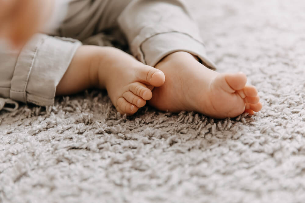 Foto que ilustra matéria sobre design sensorial mostra os pés de um bebê em destaque sobe um tapete felpudo.